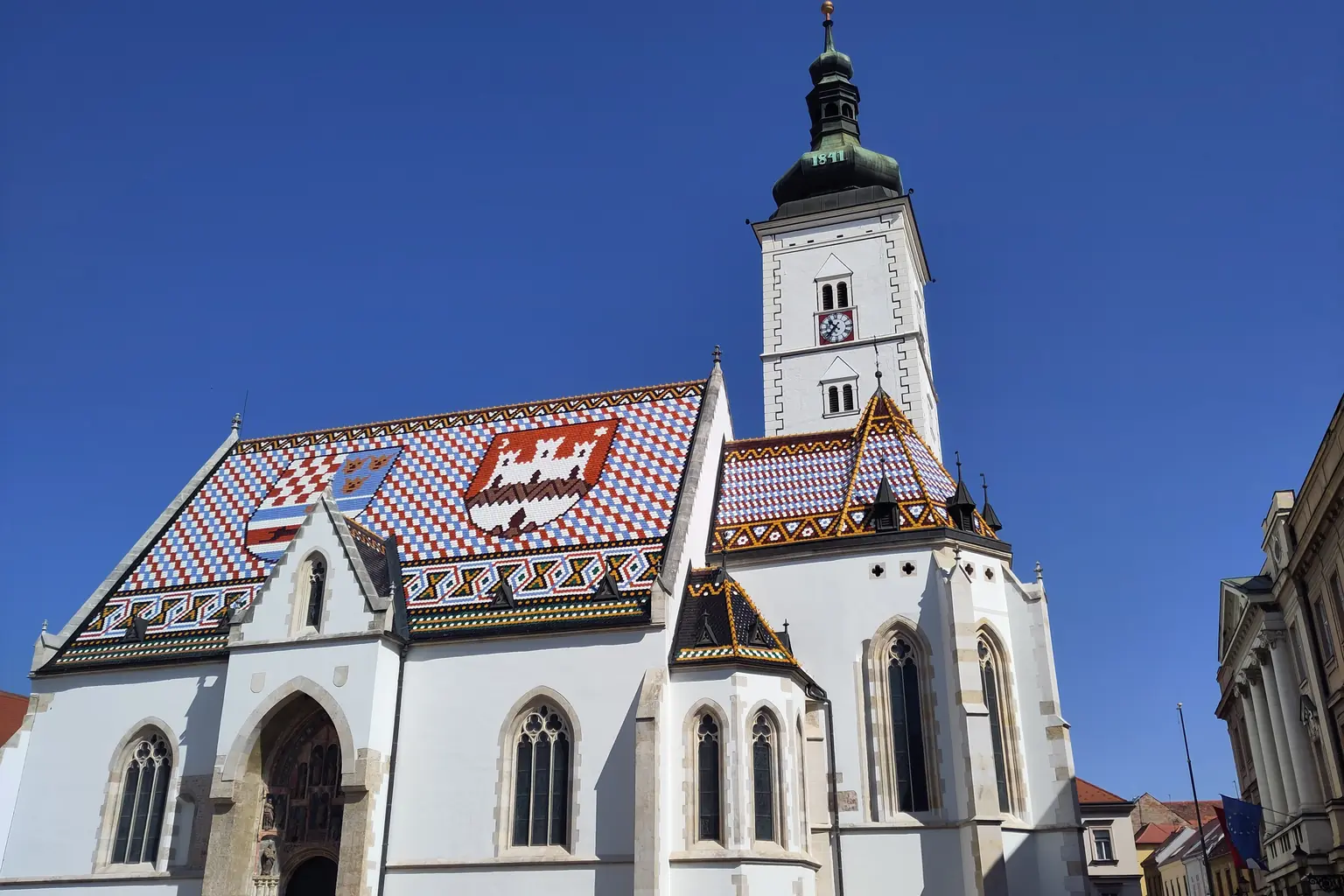 Crkva sv. Marka u Zagrebu s crijepom oslikanim hrvatskim i gradskim grbom, pod tamnoplavim nebom.